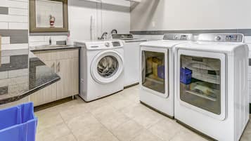 A modern laundry room with a washing machine, dryer, and countertop with a sink.