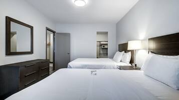 A hotel room with two beds, a dresser, a mirror, a lamp, and a ceiling light.