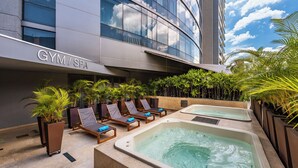 Un hotel con gimnasio y spa, mobiliario de exterior con tumbonas y una zona de piscina.