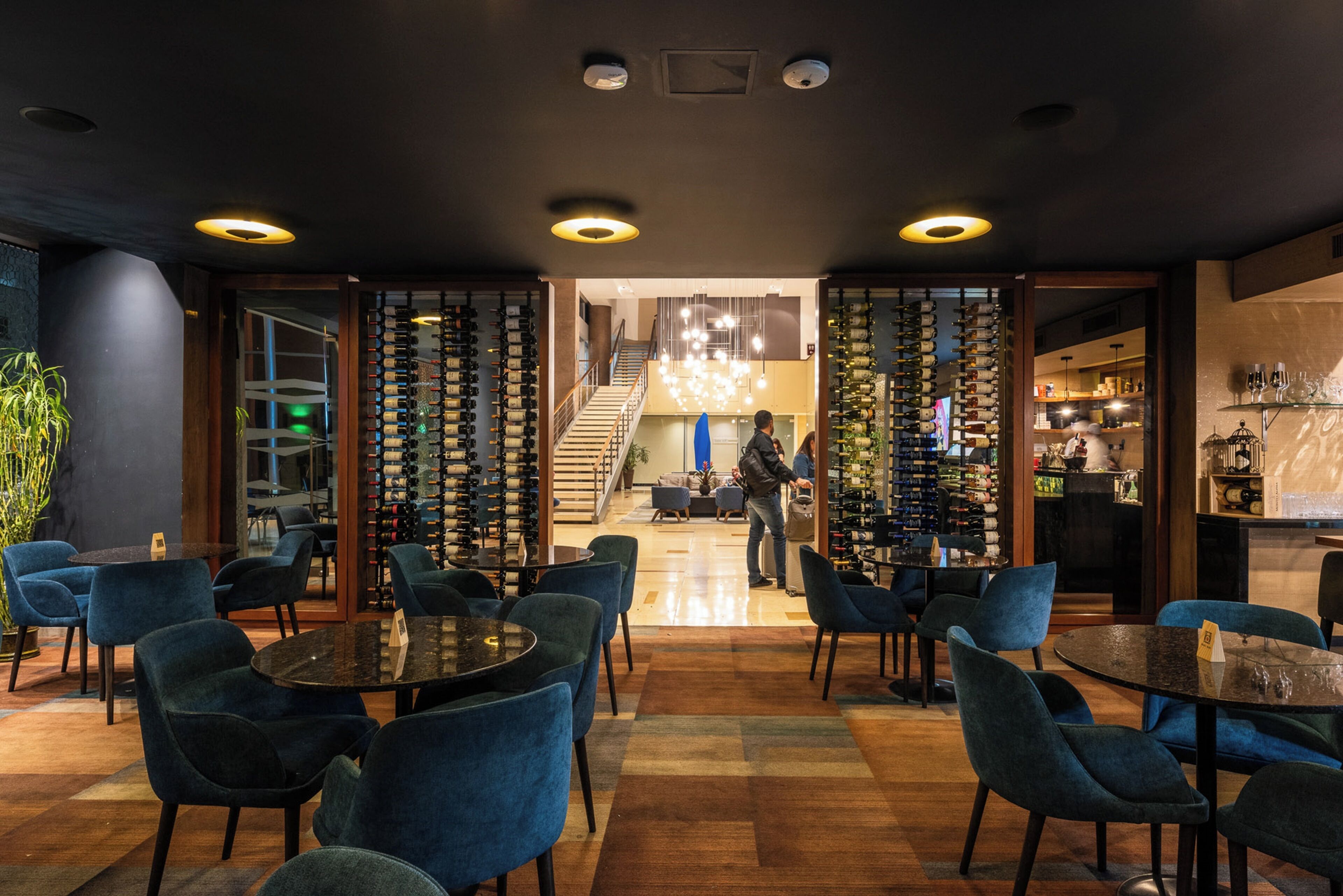 A modern interior with seating areas, a staircase, and a wine rack.