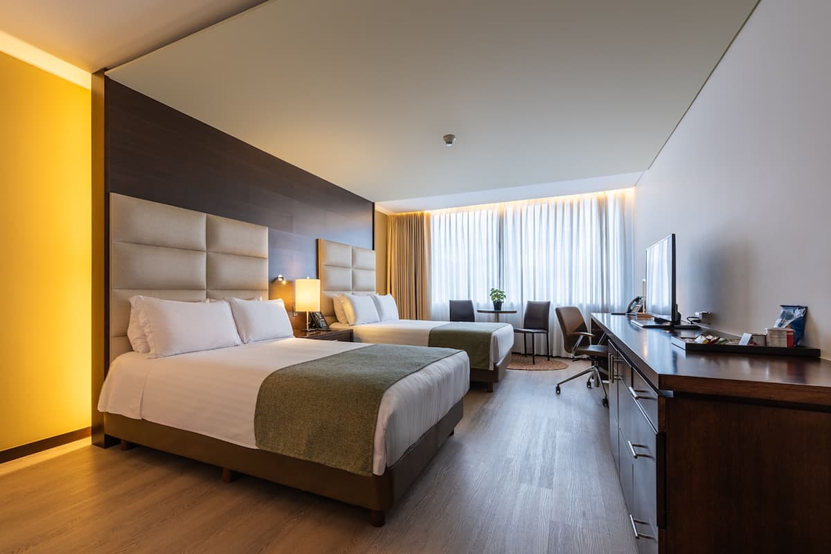 Hotellihuone, jossa on kaksi sänkyä, työpöytä ja tuoli.