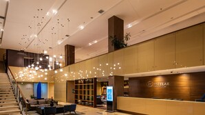 Un moderno vestíbulo de hotel con mostrador de recepción, zona de estar y una escalera.