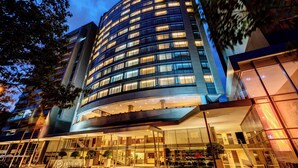 Un hotel moderno con fachada curva, varios pisos y una entrada bien iluminada.