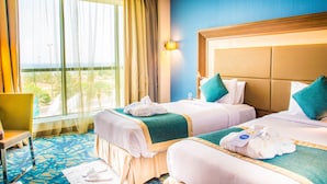 A hotel room with two beds, a large window with curtains, a chair, and a blue patterned carpet. - Novotel Yanbu (Yanbu)