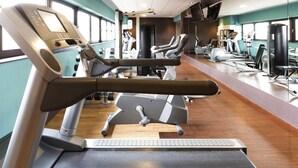 A gym with cardio machines, weight machines, and a mirrored wall.