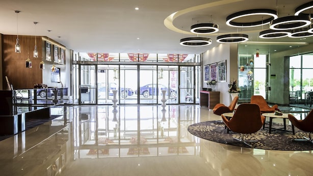 A modern lobby with a reflective floor, a reception desk, seating area, and large windows offering a view of the outside. - Novotel Yanbu (Yanbu)
