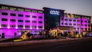 A hotel with a modern design, featuring a prominent sign and multiple flags. - Novotel Yanbu (Yanbu)