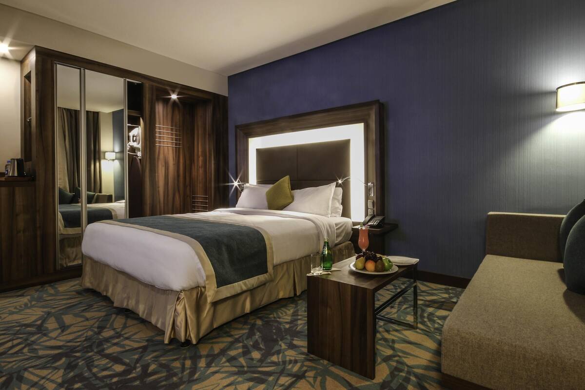 A hotel room with a bed, bedside table, and a chair.