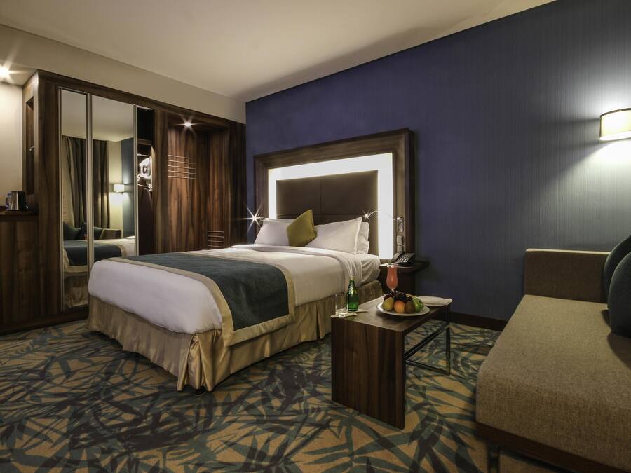 A hotel room with a bed, bedside table, and a chair.