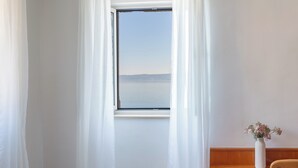 Una habitación con un ventanal grande, cortinas blancas y una pared de madera.