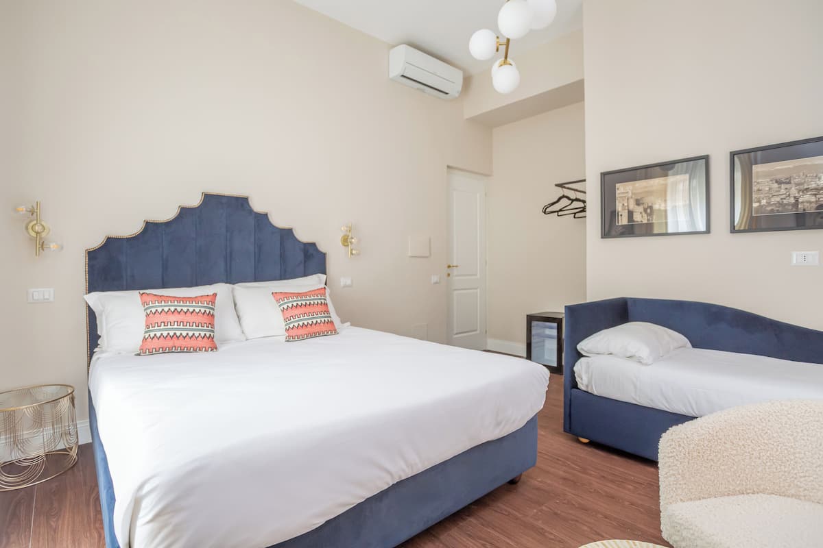 A bedroom with a large bed, two bedside tables, a sofa, and a chair.