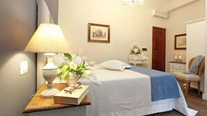 Un dormitori ben organitzat amb un llit, una taula de nit, una làmpada i un vas de flors.