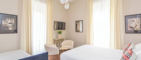 A hotel room with a bed, two chairs, a small table, and a TV.