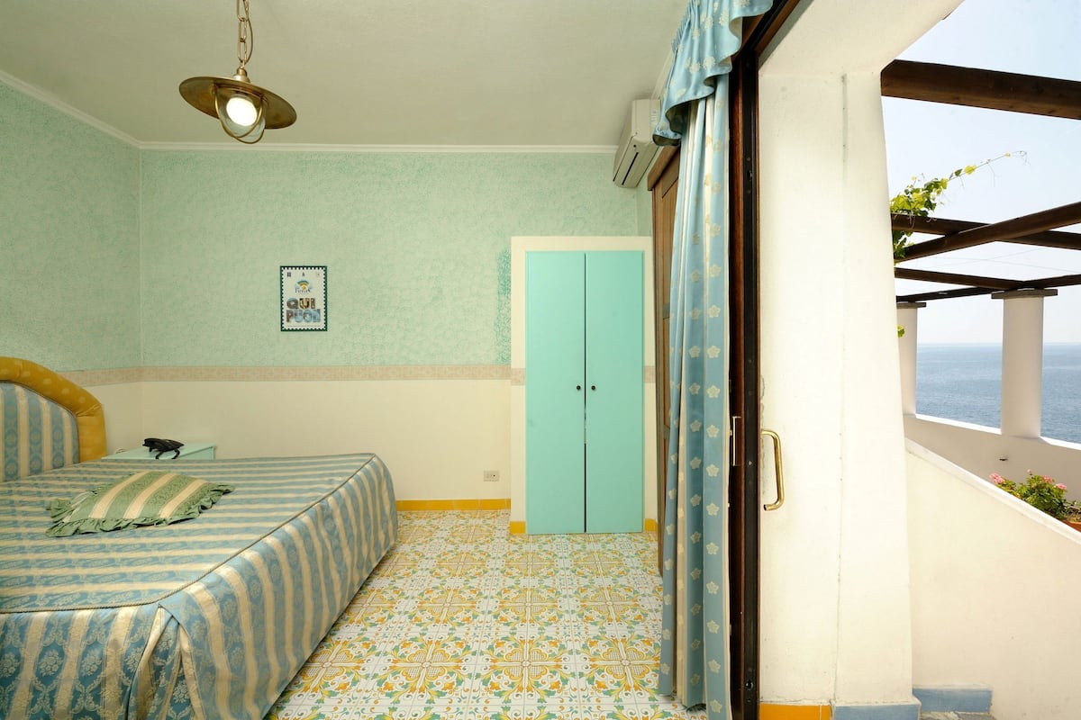 A bedroom with a bed, a wardrobe, and a window with a view.