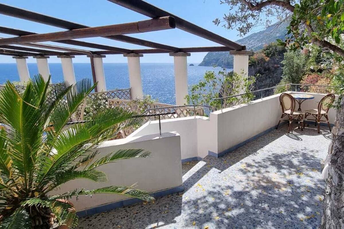 A terrace with a view of the sea, a pergola, and outdoor seating.