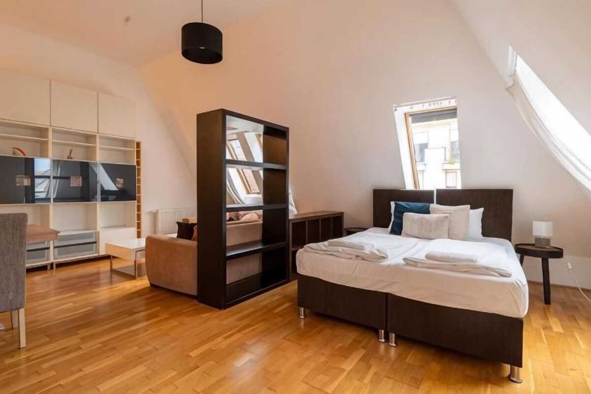 Un dormitorio con cama, estantería, escritorio y ventana.