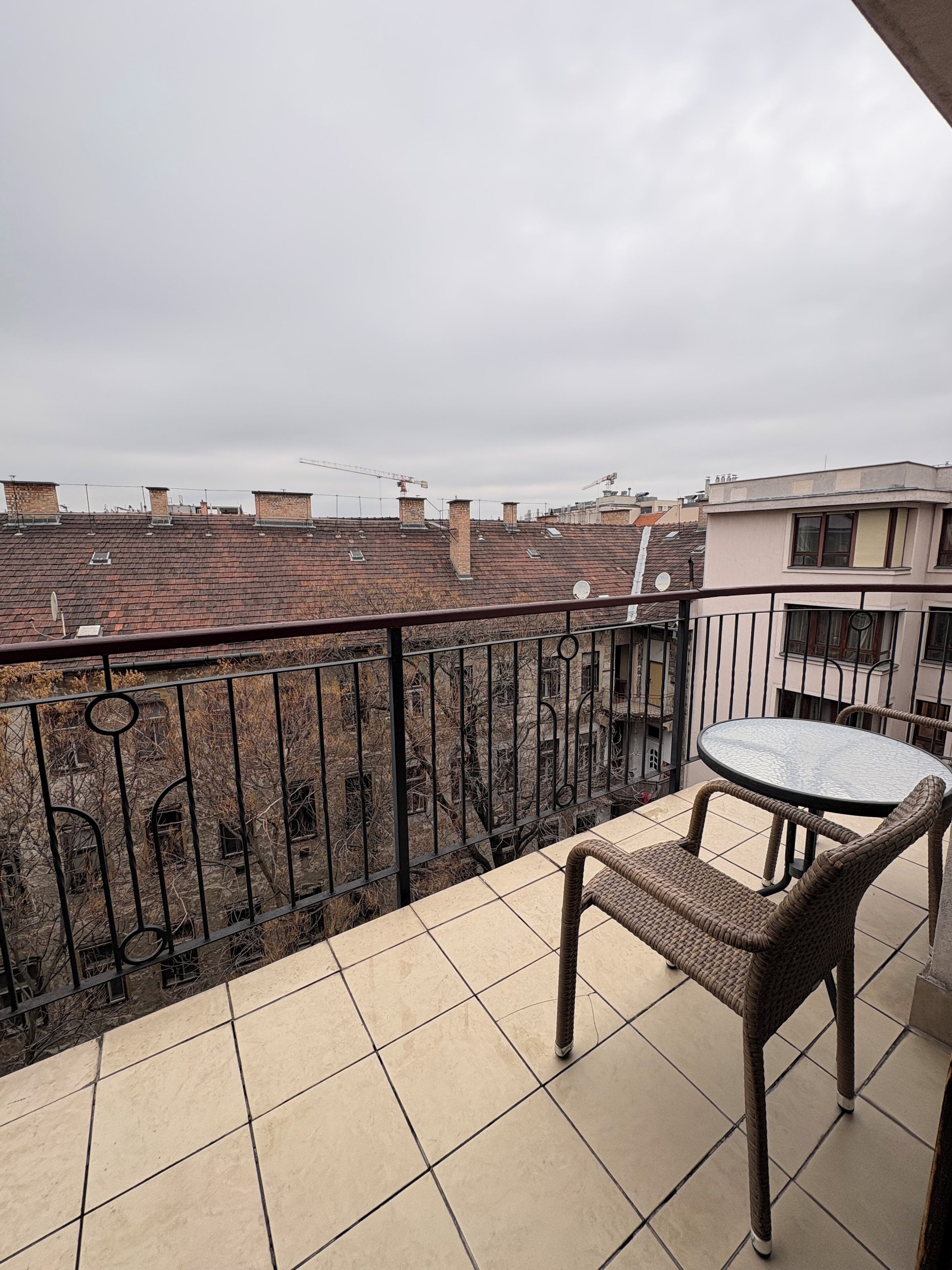 Ein Balkon mit Fliesenboden, einem Metallgeländer und einem Tisch mit zwei Korbstühlen.