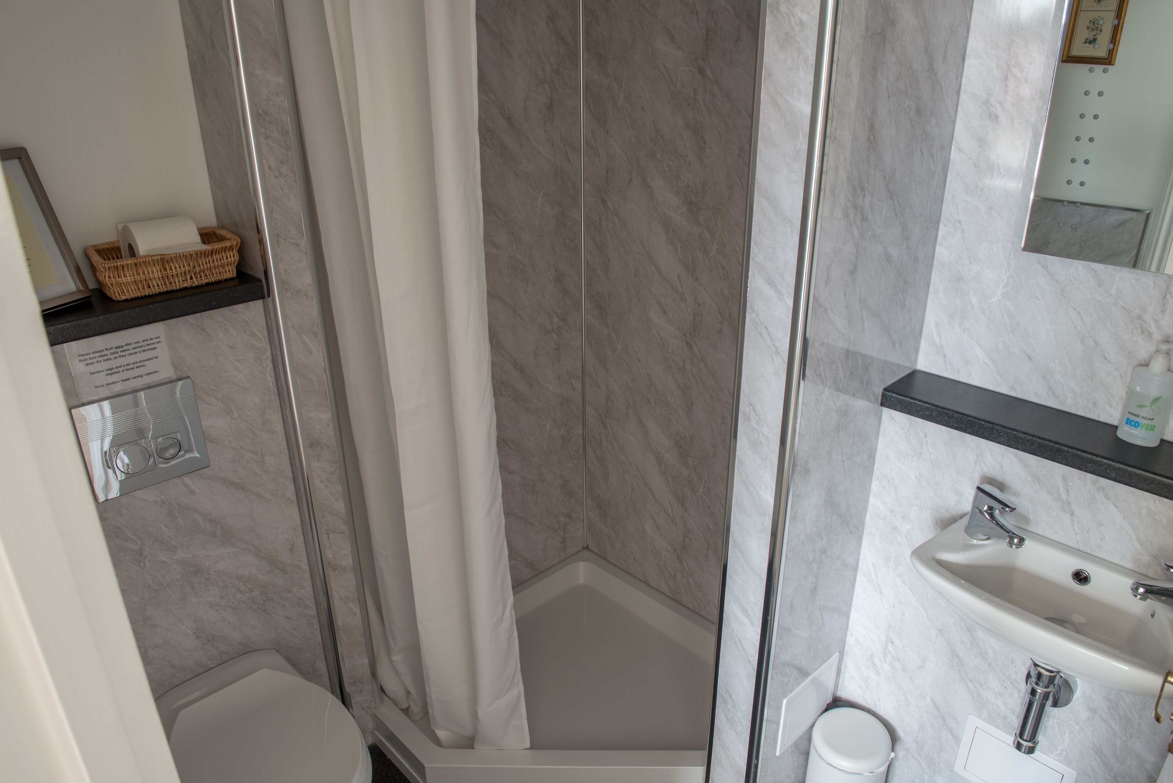 Une salle de bain avec douche, toilettes et lavabo.