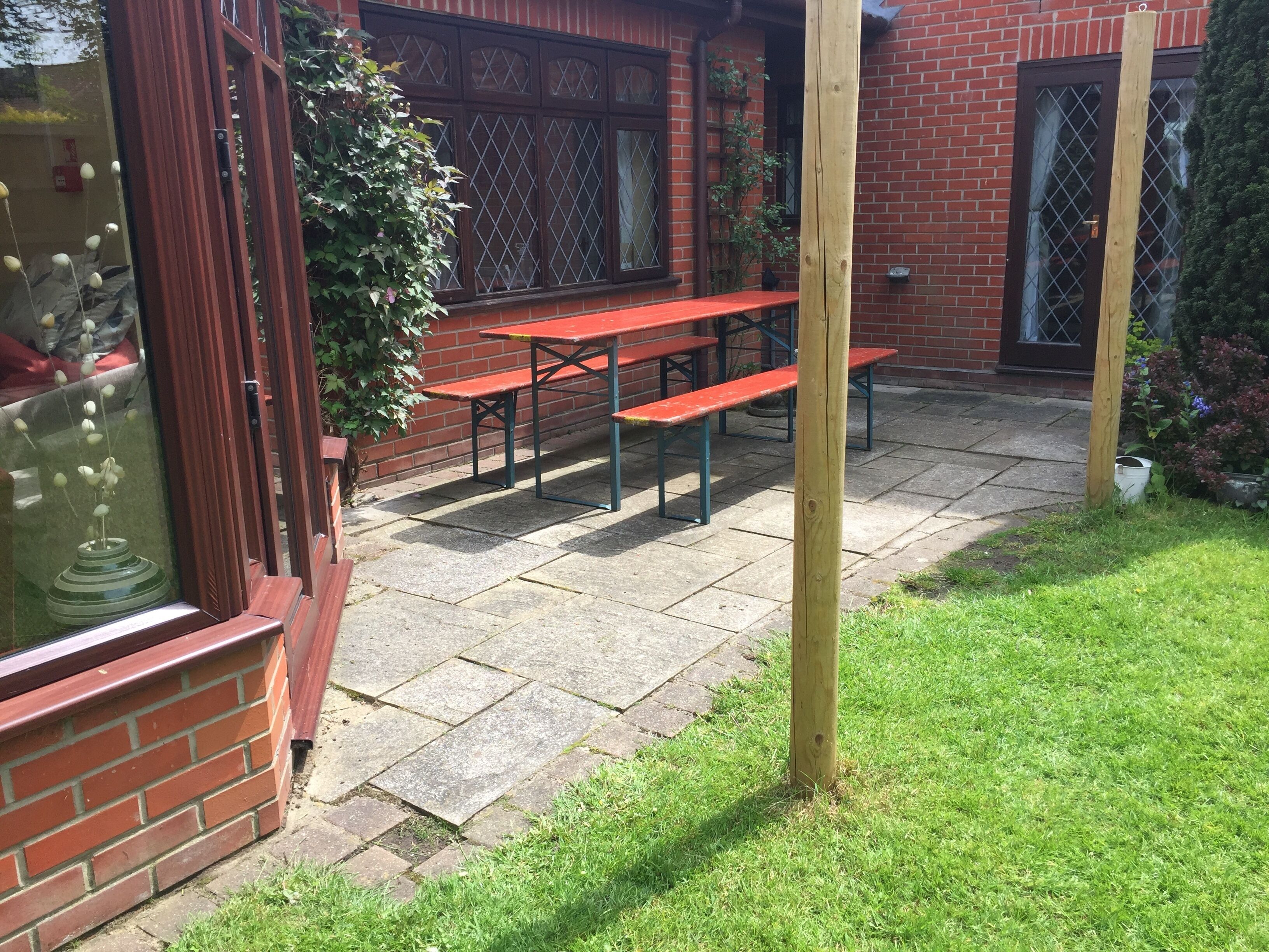A patio area with a brick wall, a wooden post, and a red bench.
