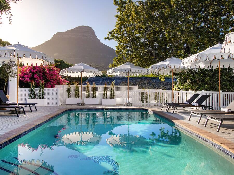 Una piscina al aire libre, sombrillas, sillones reclinables de piscina
