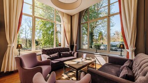 Un salón amplio con un gran ventanal, un sofá, dos sillones y una mesa de centro.