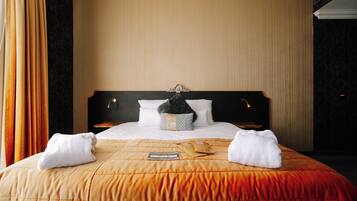 Quarto de hotel com uma cama grande, cabeceira e mesa de cabeceira.