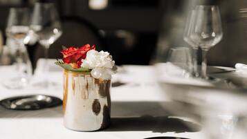 Una mesa de comedor con un florero y copas de vino vacías.