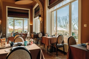 Un restaurante con varias mesas, sillas y vistas al exterior.