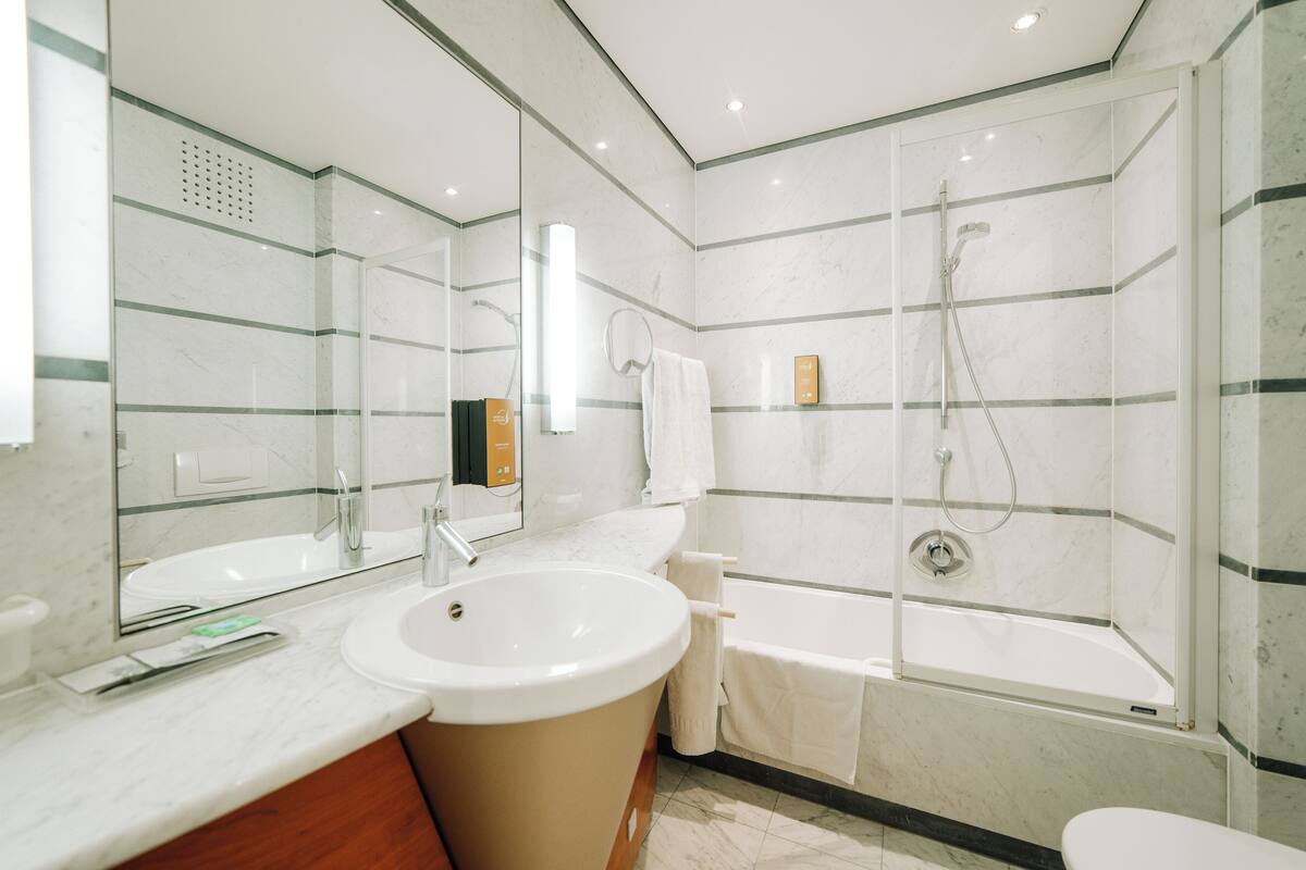 A modern bathroom with a large sink, mirror, and a walk-in shower.