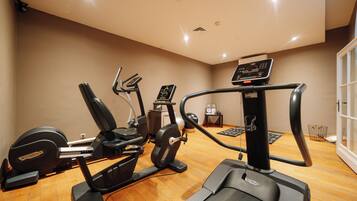 Un gimnasio con diversas máquinas de ejercicio, una cinta de correr y una bicicleta estática.