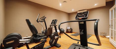 Un gimnasio con diversas máquinas de ejercicio, una cinta de correr y una bicicleta estática.