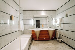 Un baño moderno con tocador doble, bañera y espejo grande.