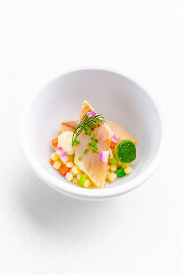 A white bowl containing a seafood dish with various vegetables and garnishes. - Château de Namur (Namur)