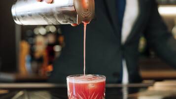 A bartender pouring a drink into a glass.