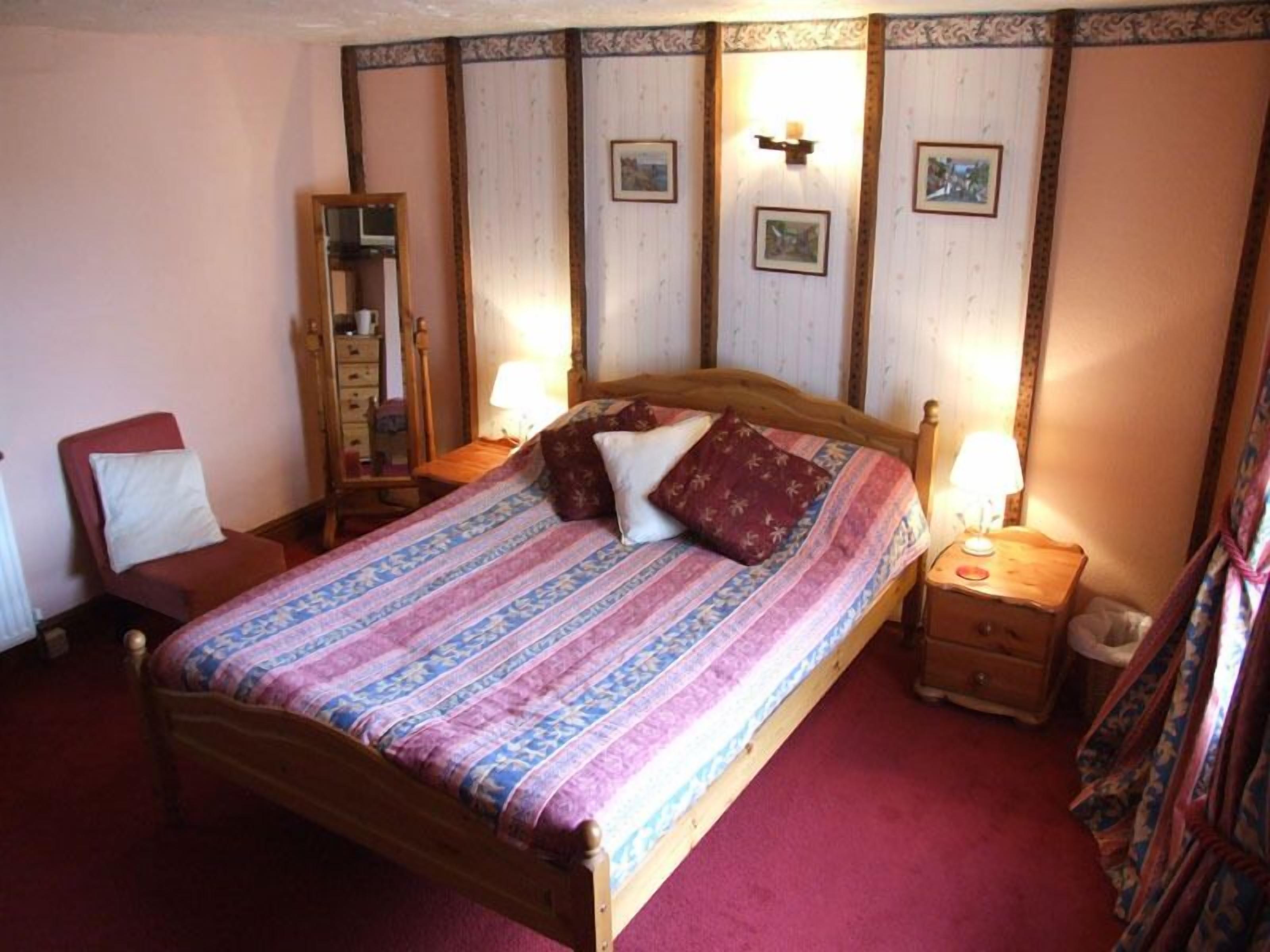 Un dormitorio con una cama de madera, una mesita de noche, una silla y un armario.