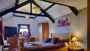 A bedroom with a wooden bed, a dresser, a television, and a wardrobe. - The West Country Inn (Bideford)