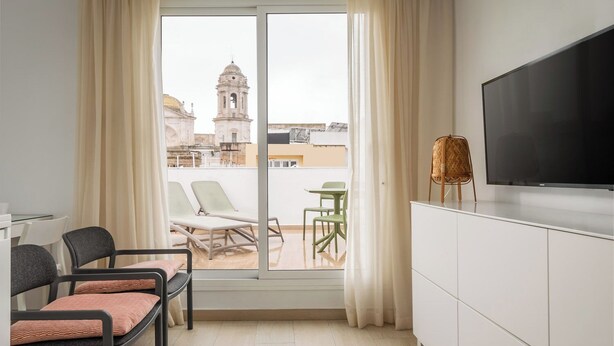 Una habitación moderna con balcón, televisión y zona de estar.