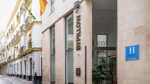 Entrada de hotel con un letrero que dice "Bypilon" y un letrero azul en forma de "H" que indica un hotel.