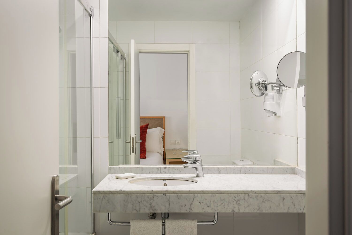 Un baño moderno con lavamanos doble, cabina de ducha con mampara de vidrio y un espejo grande.