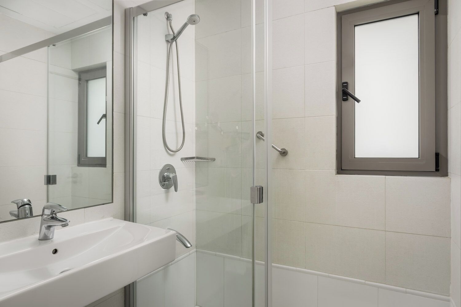 A modern bathroom with a glass shower enclosure, a white sink, and a mirror.