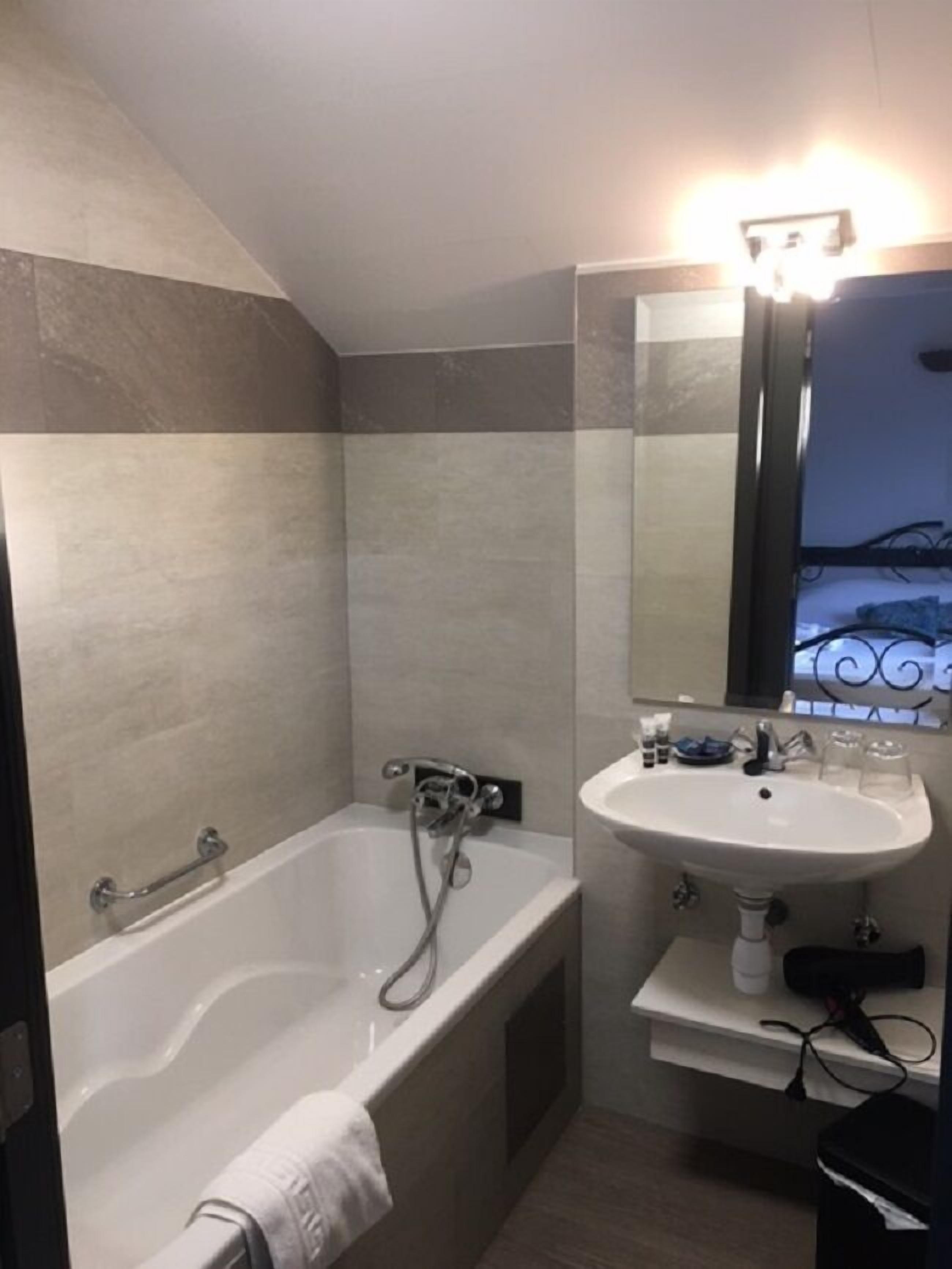 Un baño moderno con bañera, lavamanos y espejo.