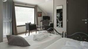 Habitación de hotel con dos camas, un escritorio, una silla, un televisor y una ventana con cortinas.