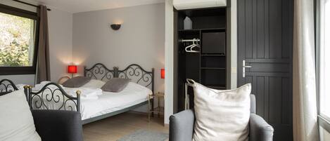 A bedroom with a bed, a chair, a glass table, a wardrobe, and a window.