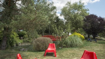 Relax by the serene pond surrounded by lush greenery and a variety of trees.