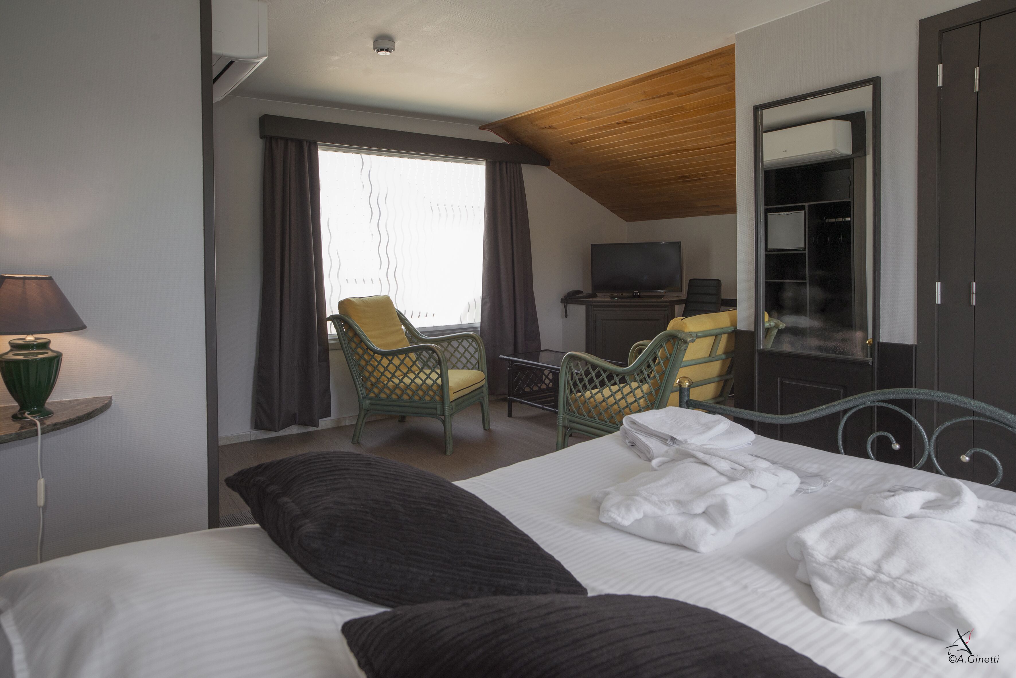Una camera d'albergo con un letto, due poltrone, una televisione e un armadio.