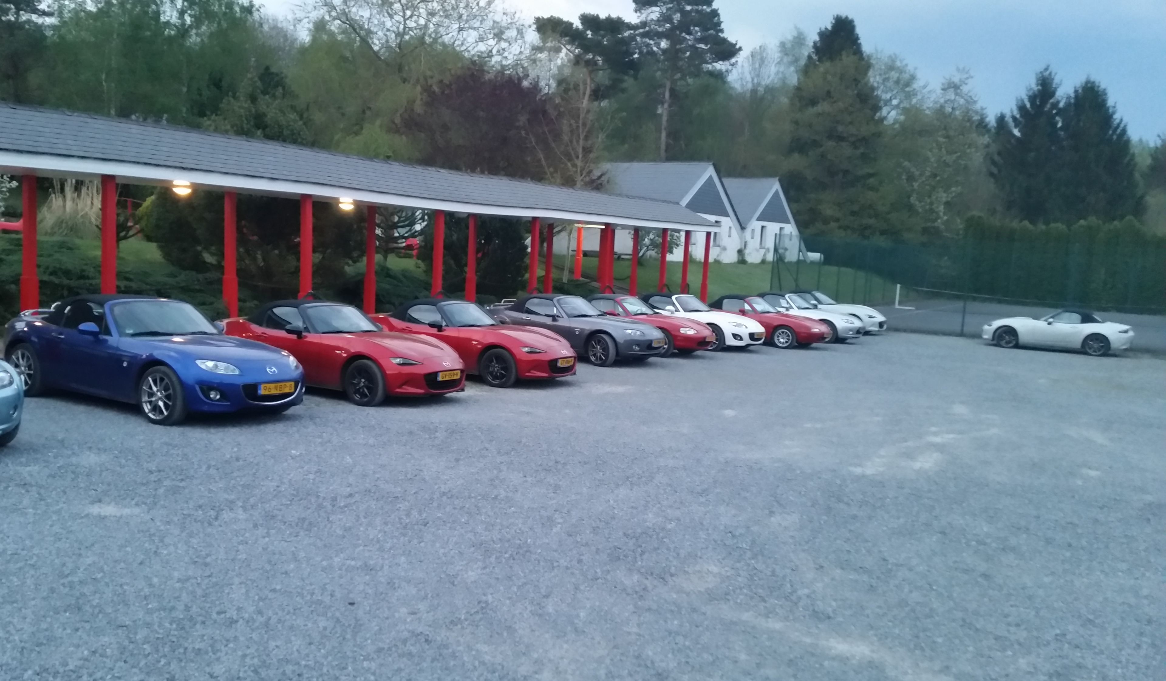 A row of parked sports cars in a covered parking area with a building in the background.
