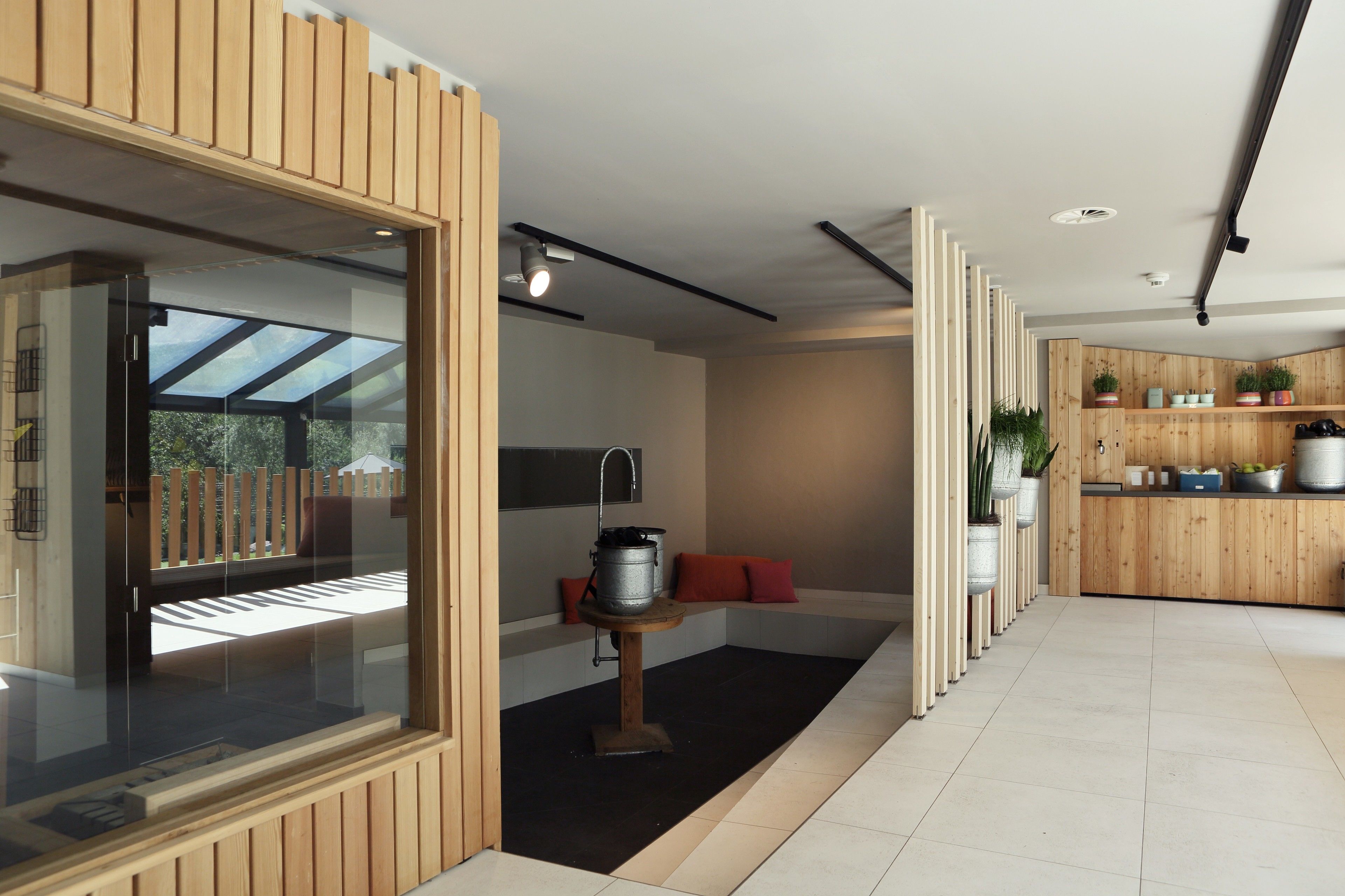A modern kitchen with wooden cabinetry, a built-in stove, and potted plants.