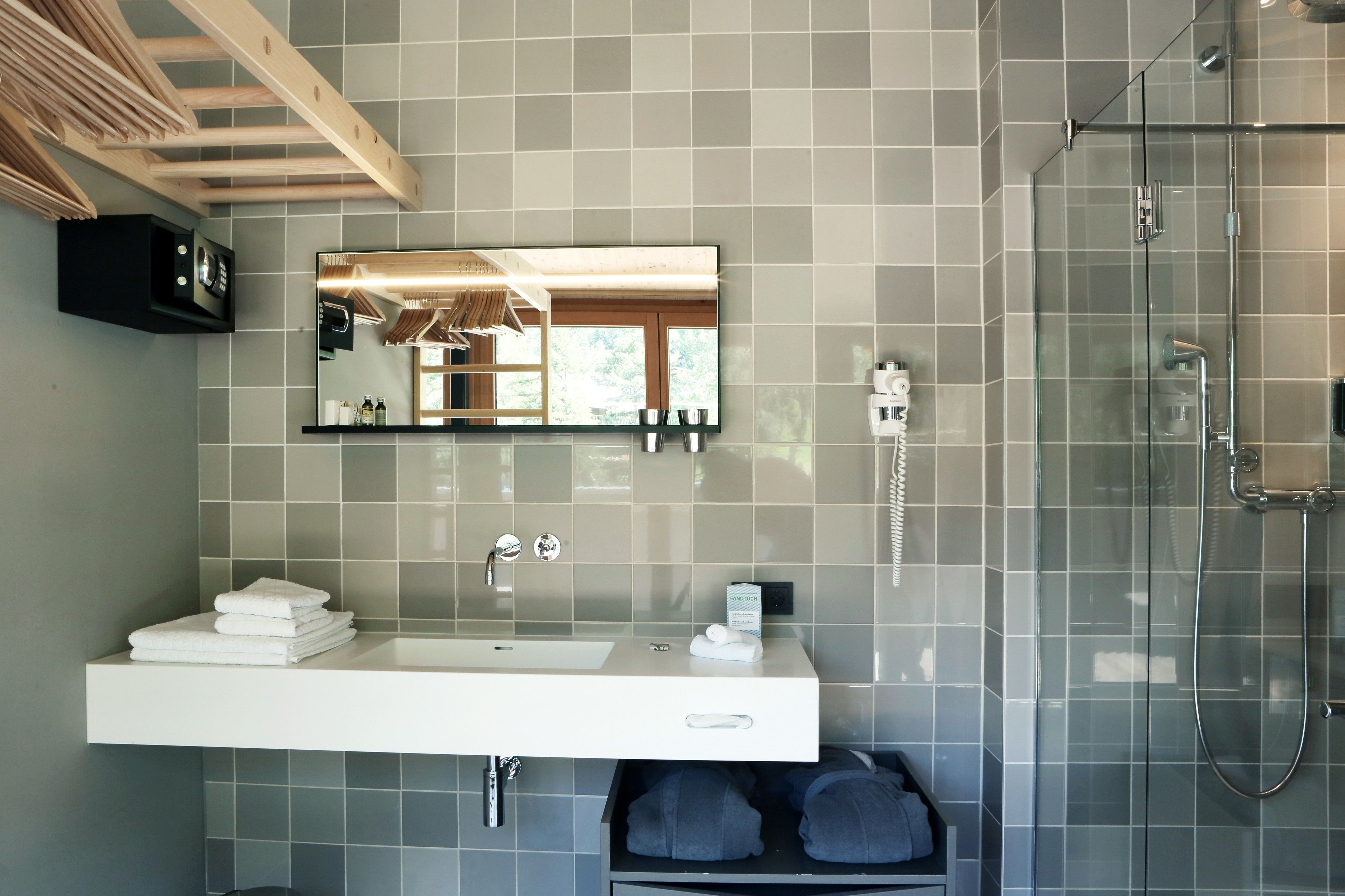 A modern bathroom with a large mirror, a sink, and a glass-enclosed shower.