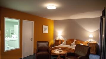 Ett hotellrum med en säng, två stolar, ett litet bord och två sänglampor.
