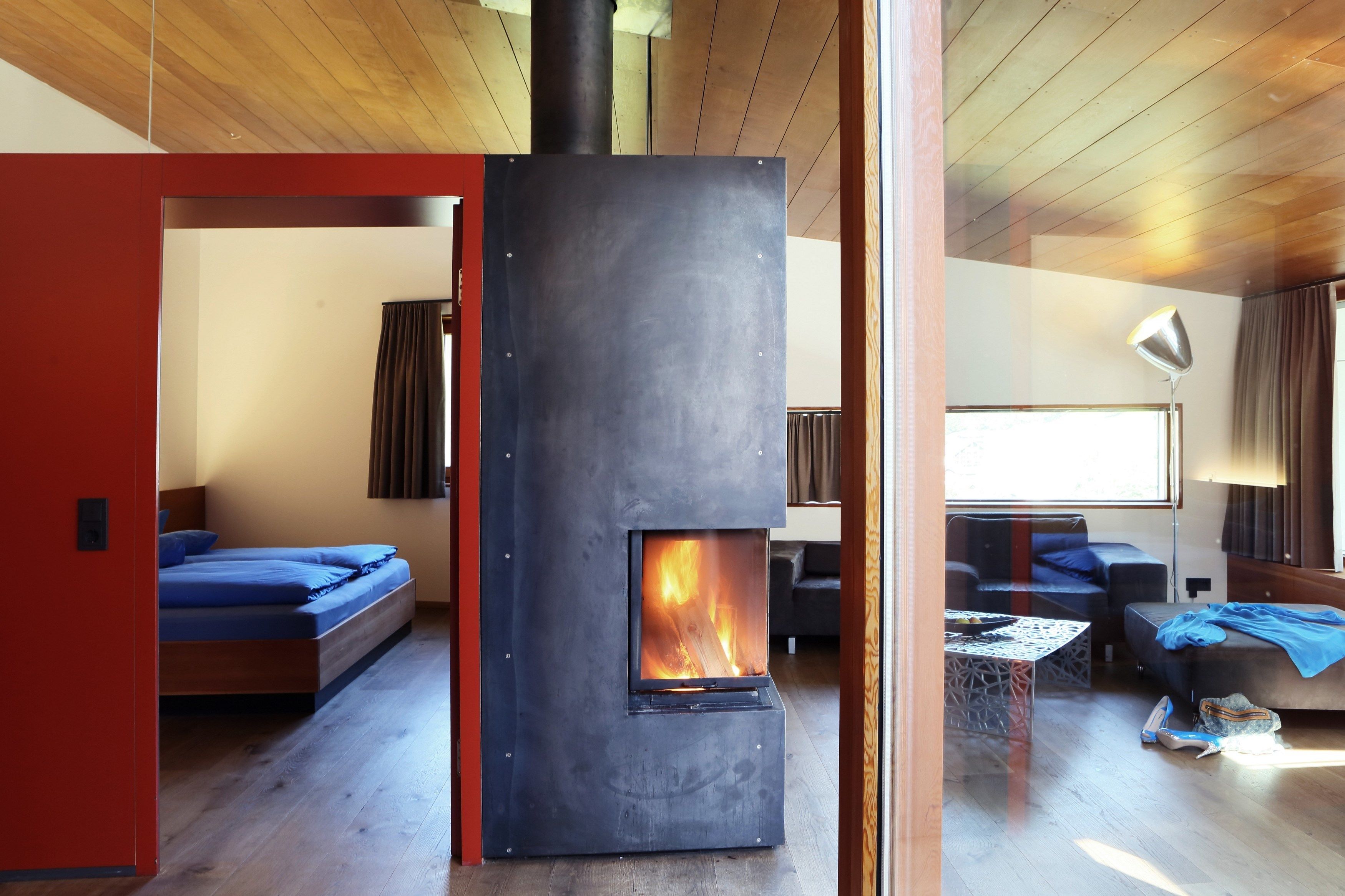 Una sala de estar moderna con una chimenea de leña, un sofá, una mesa de centro y una ventana con cortinas.